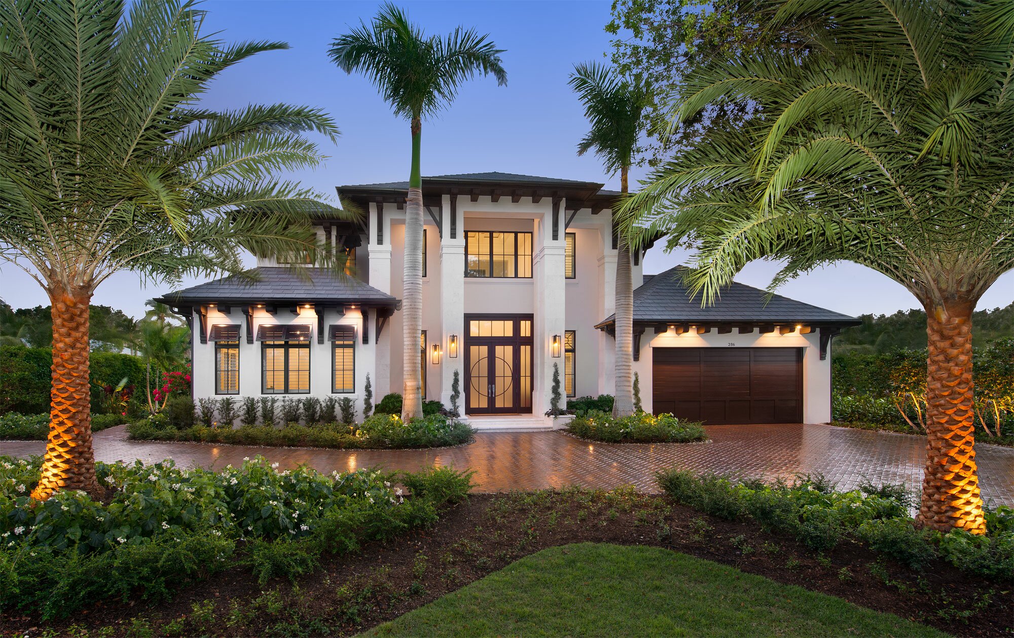 Elegant modern two-story house with palm trees and well-manicured landscaping.
