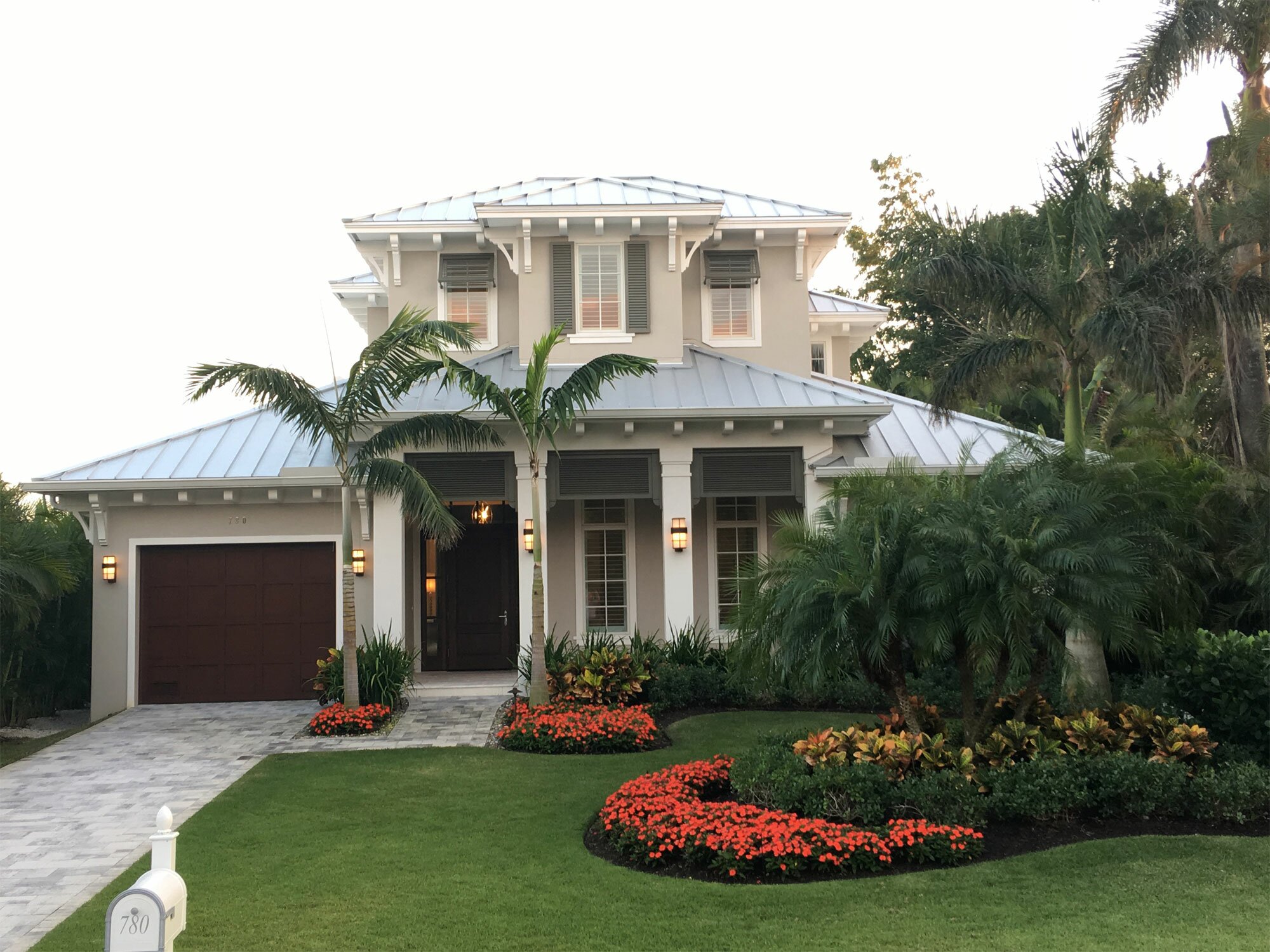 Elegant two-story house with lush landscaping and vibrant flowers.